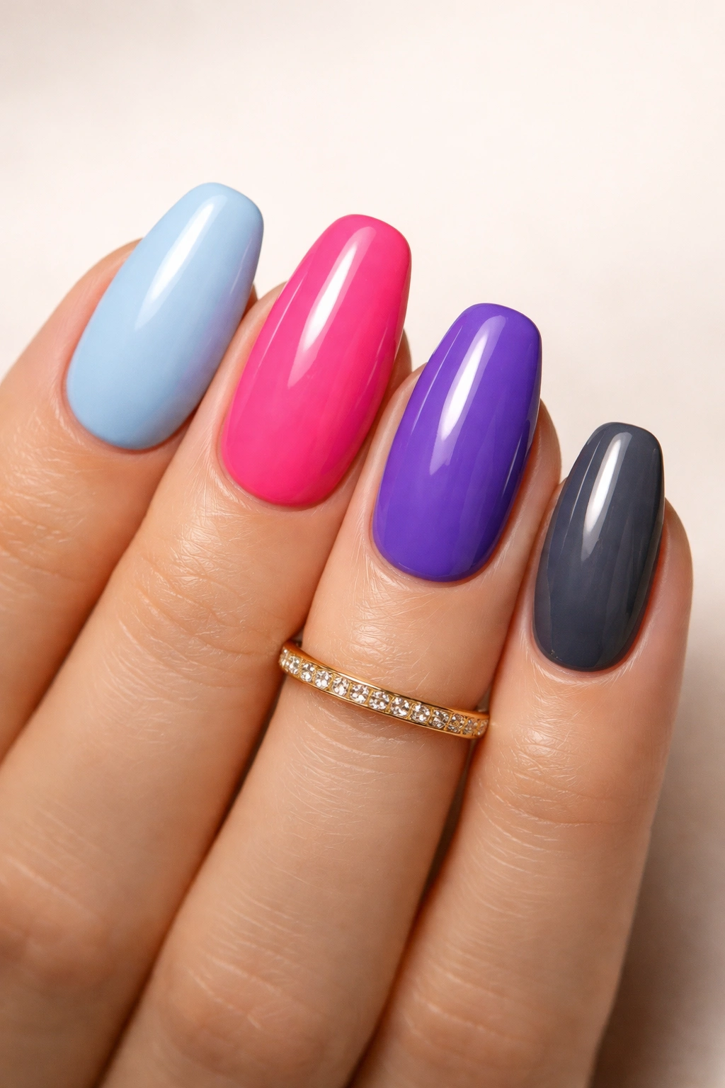 Nails in icy blue, neon pink, blue-purple, and charcoal with a gold ring