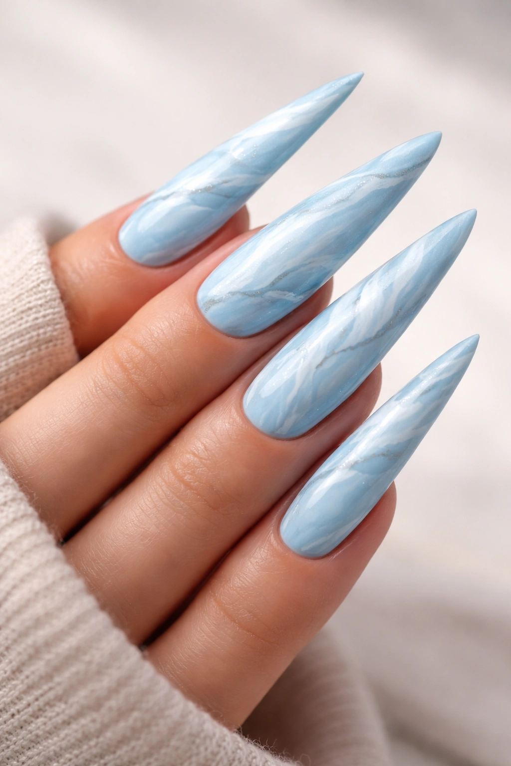 Sky blue marble nails with white veining on stiletto nails