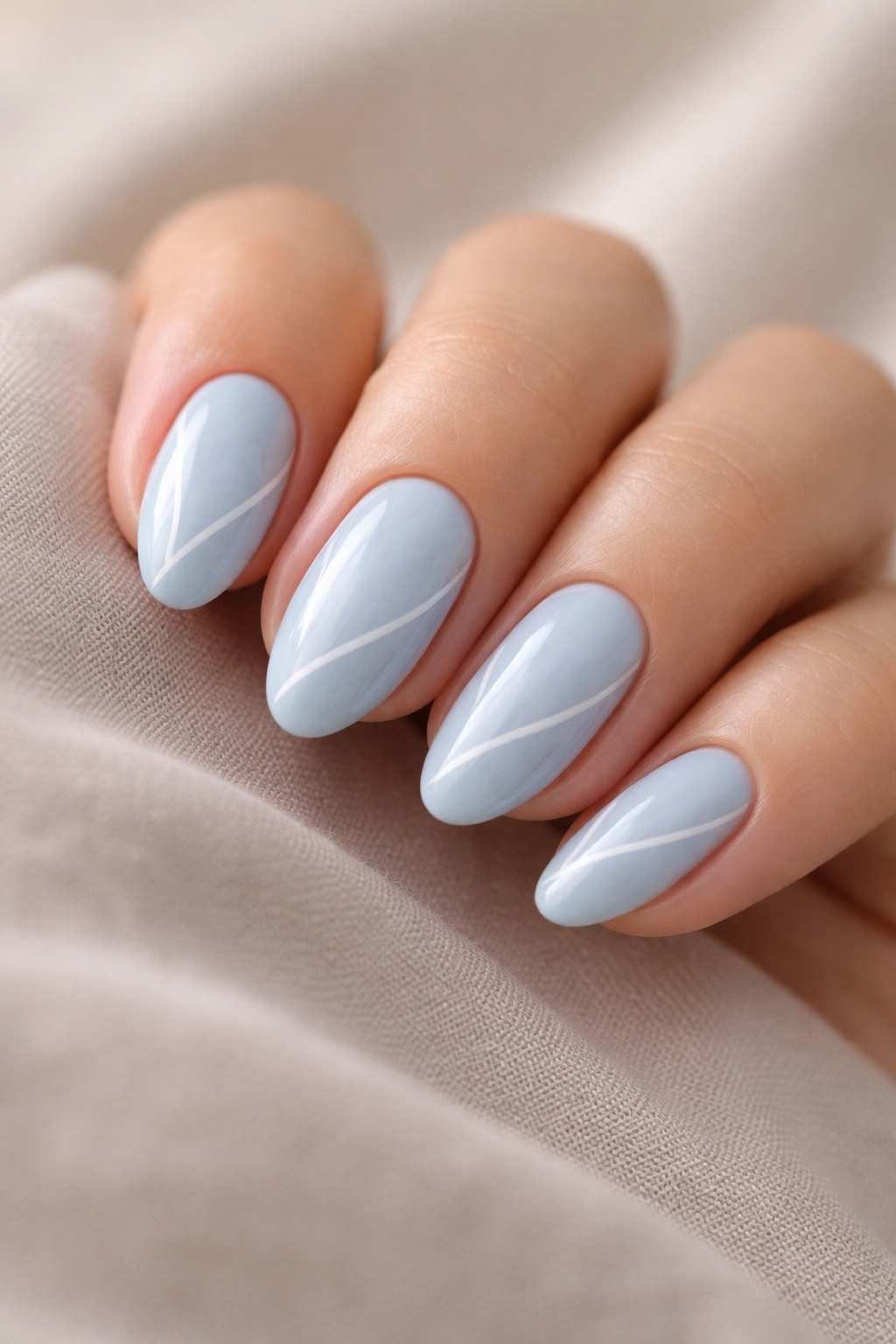 Close-up of sky blue almond nails with delicate white line art.