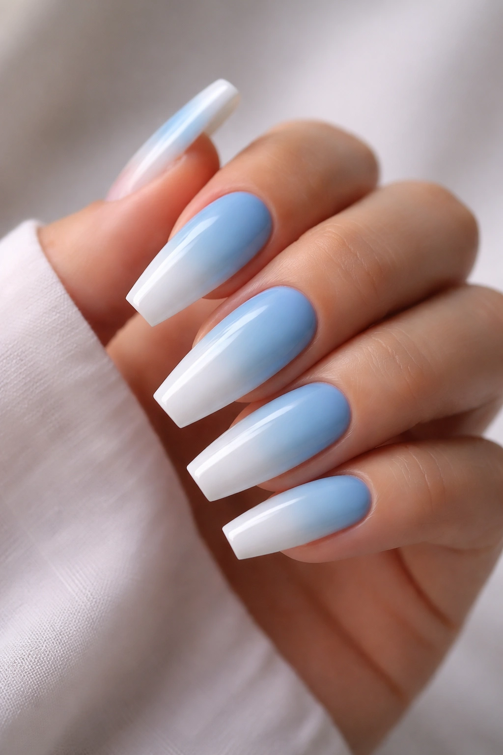 Coffin nails gradient from sky blue to white on a hand