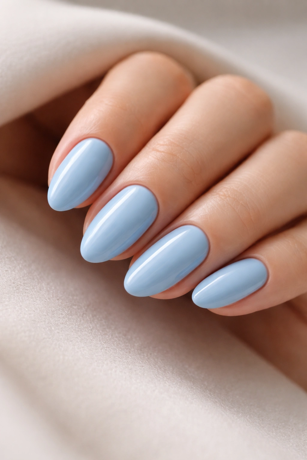Close-up of glossy sky blue short almond nails with a clean taper