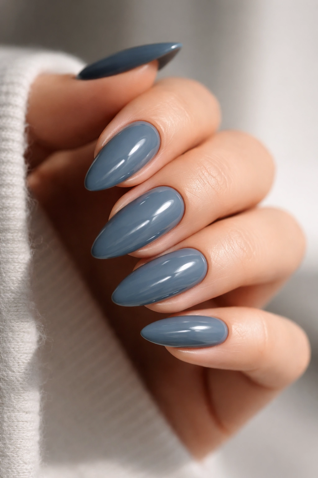 Close-up of slate blue almond nails with moody cool tone and high gloss