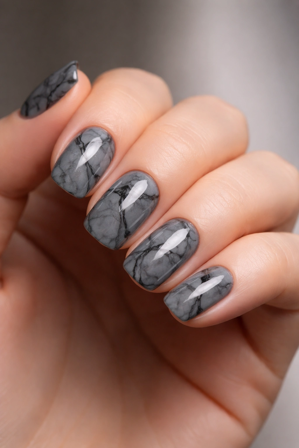 Close-up of slate gray marble nails with black veining on squoval shapes