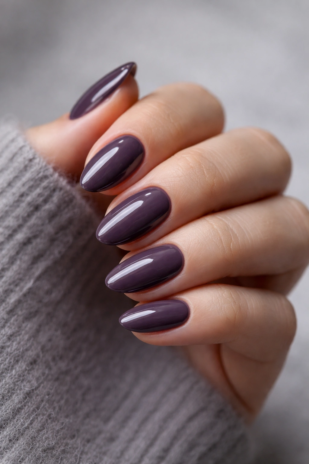 Close-up of smoky aubergine almond nails on a bare hand