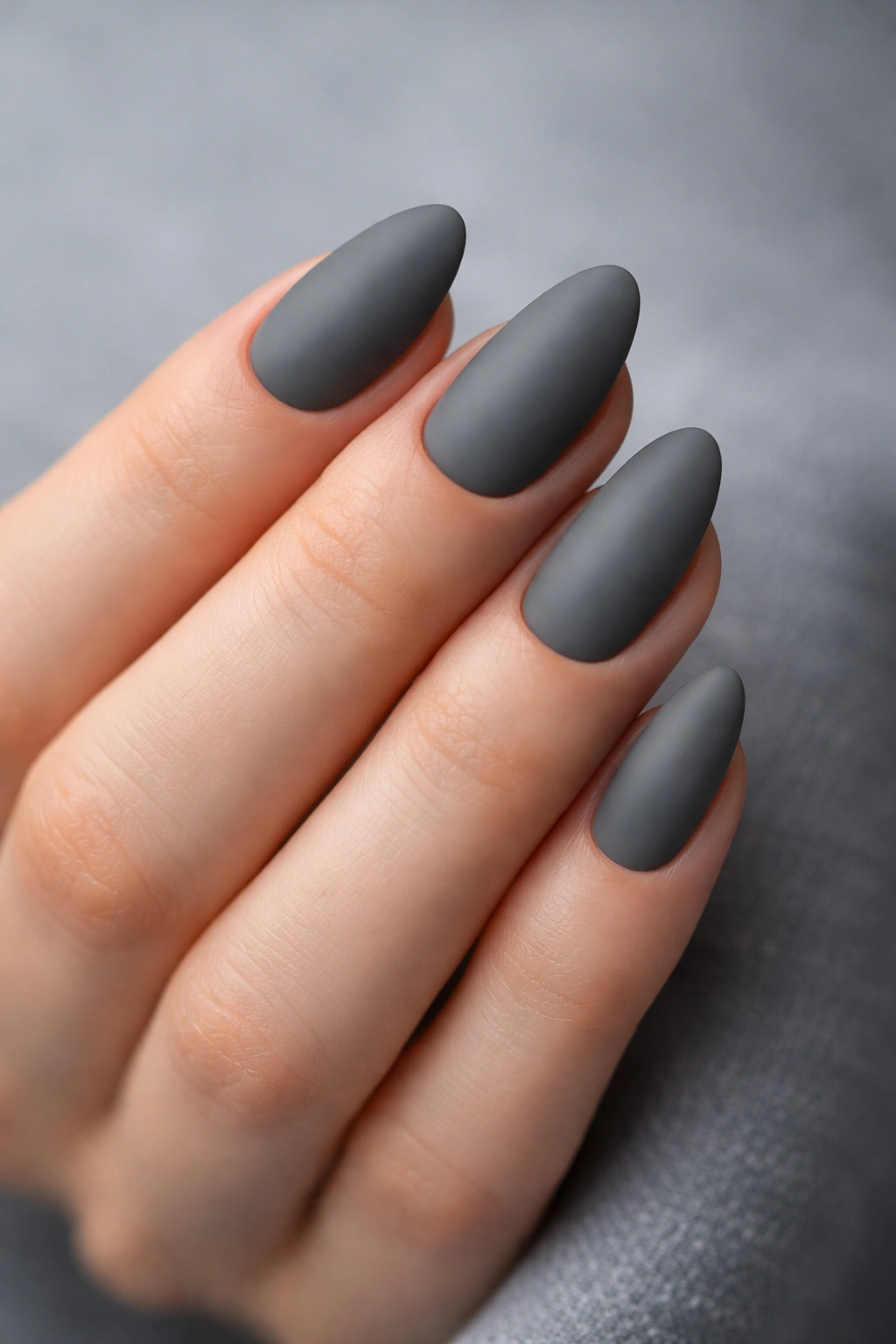 Close-up of short almond nails in smoky gray matte finish