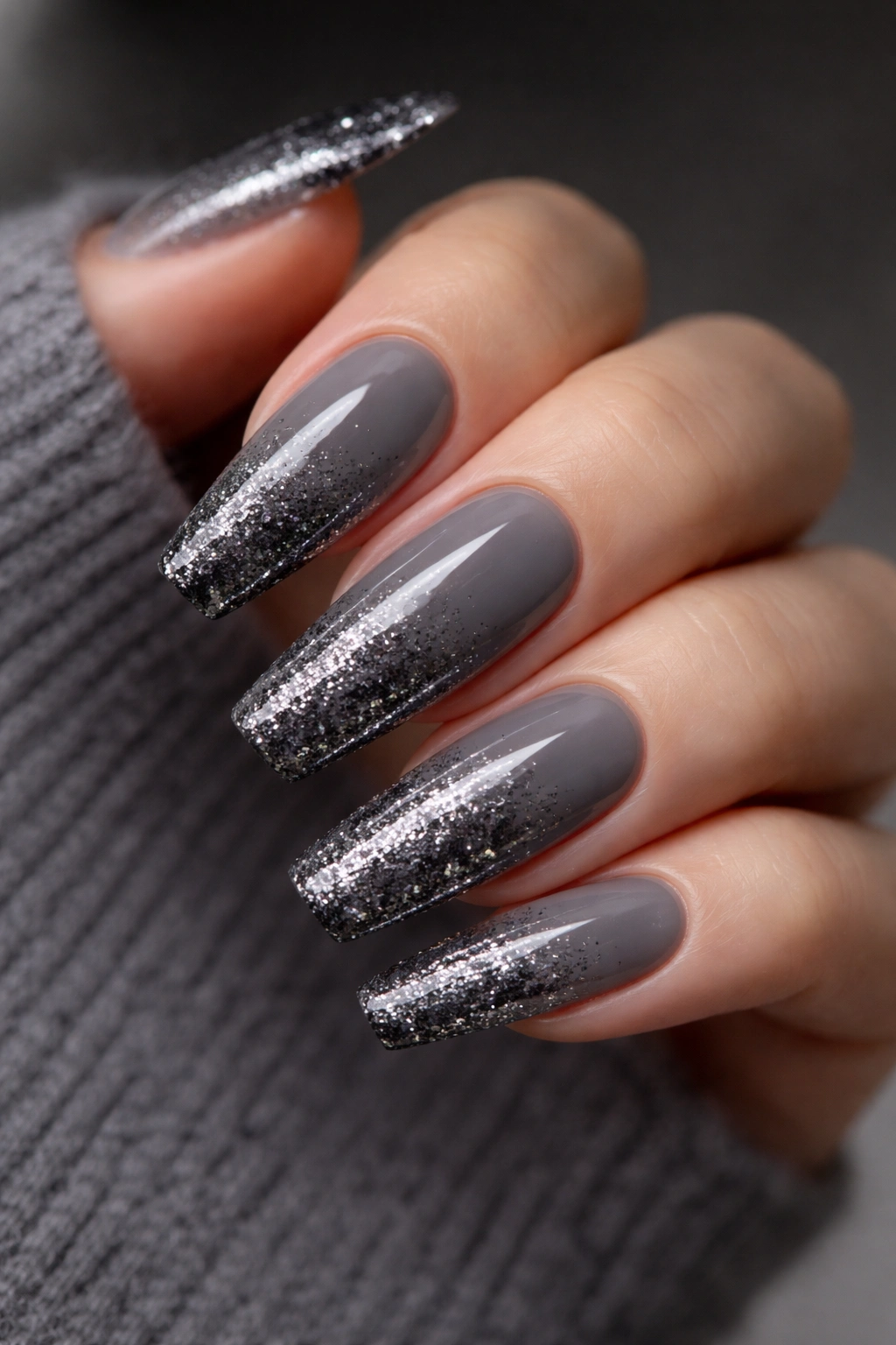Smoky gray nails with gunmetal glitter fade on a neutral background