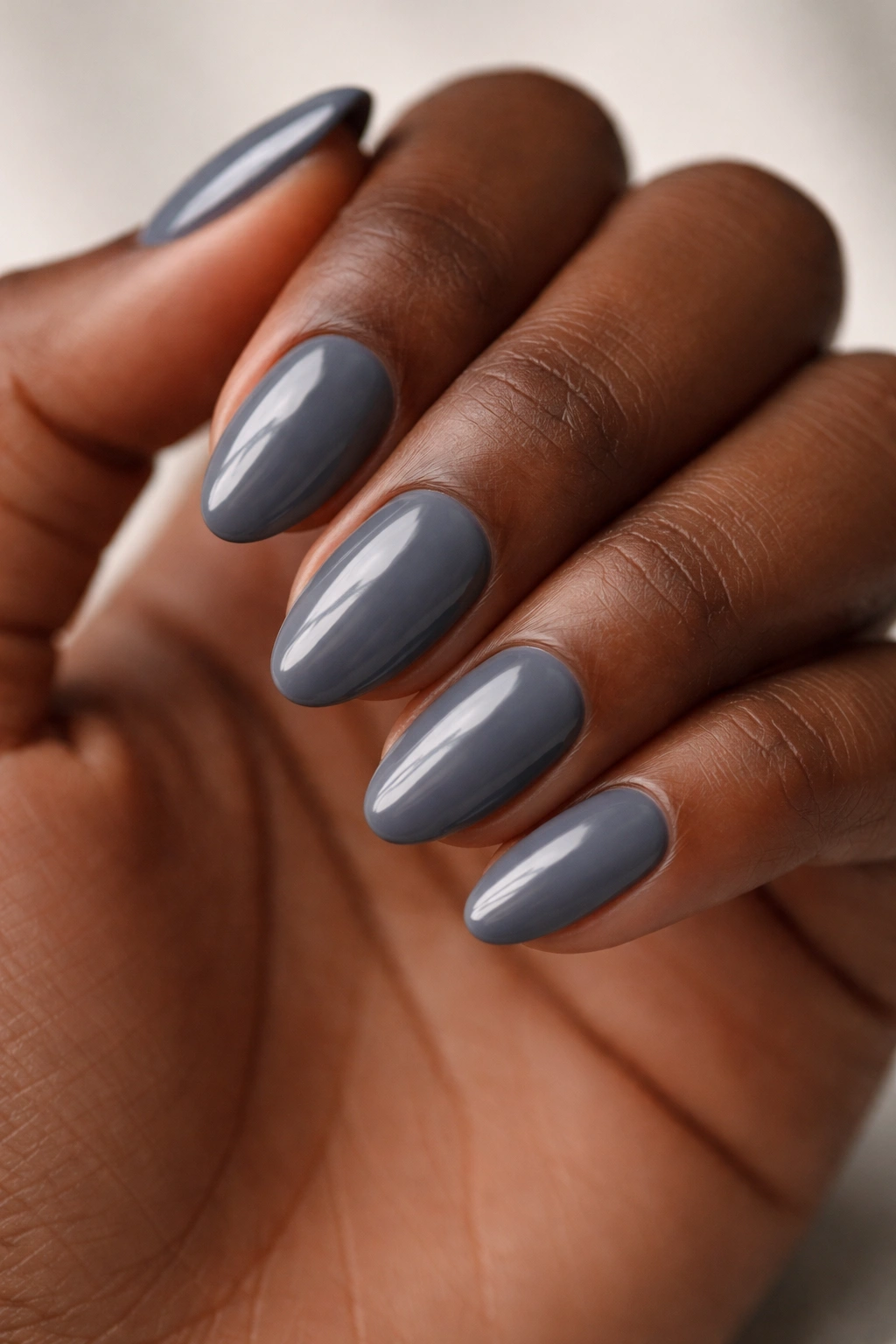 Close-up of smoky gray short almond nails on dark skin hand