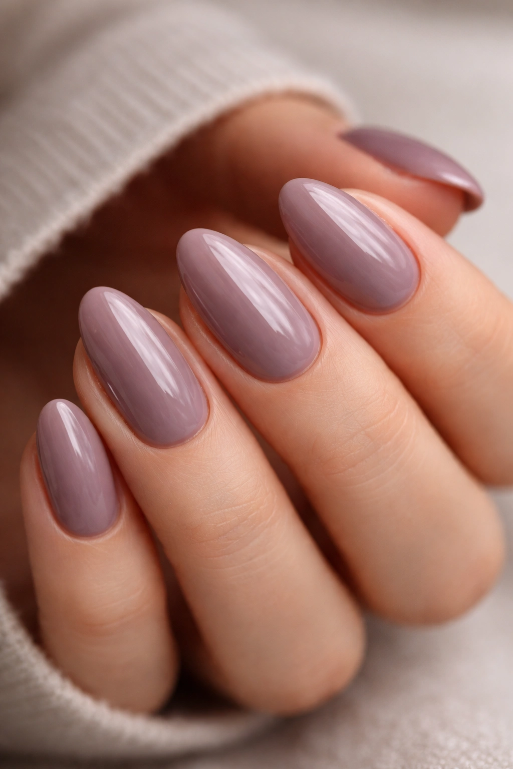 Close-up of short almond nails in smoky mauve with glossy finish