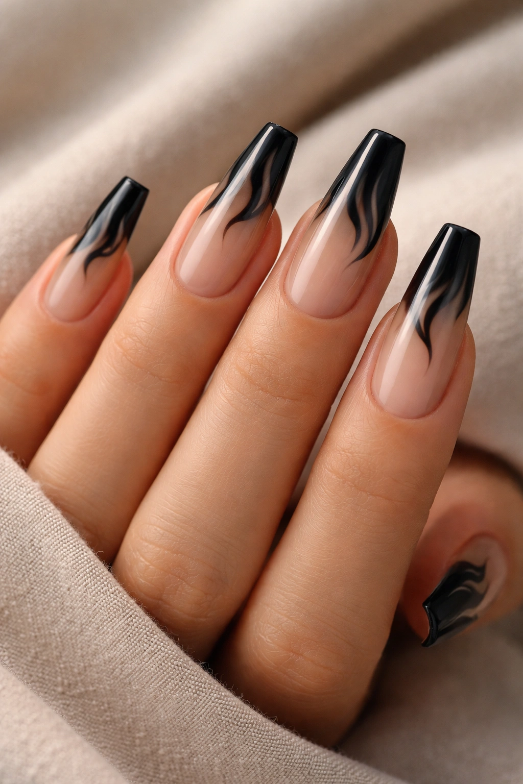 Close-up of smoky nude base nails with black flame tips on a ballerina shape