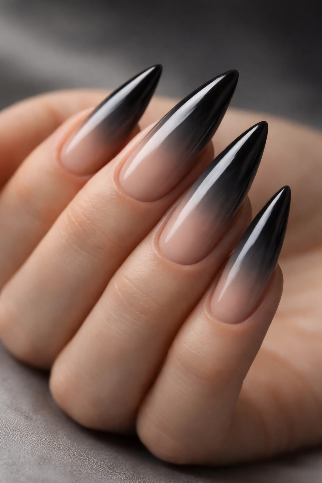 Close-up of smoky ombre stilettos nails with charcoal gray to nude gradient