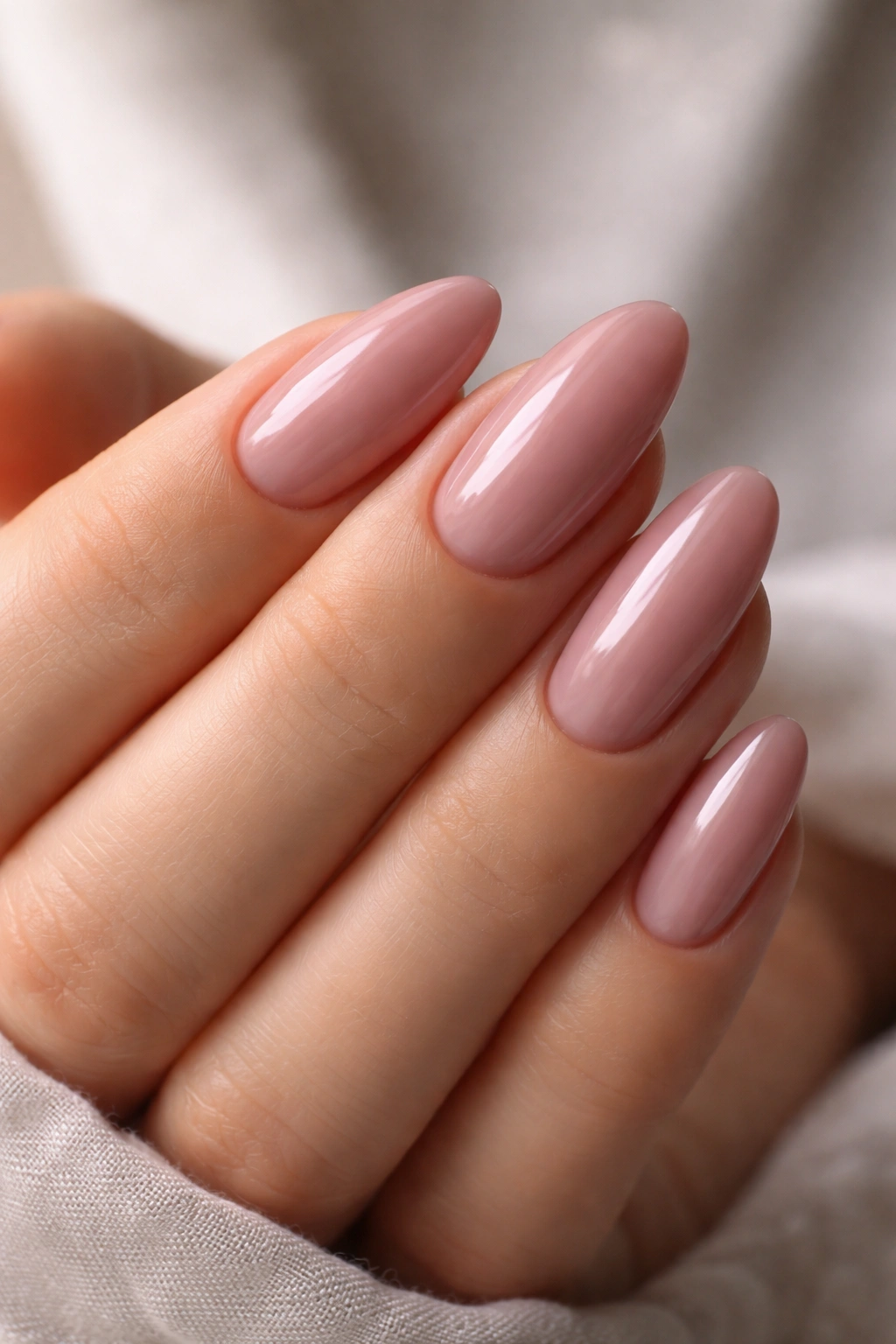 Close-up of short almond nails in smoky pink glaze, soft mauve-pink shade