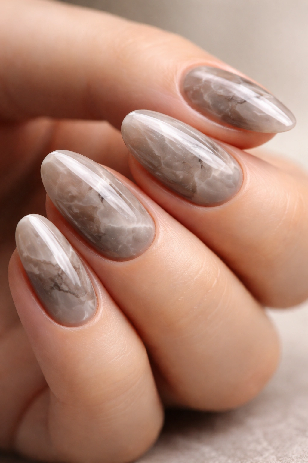 Close-up of smoky taupe marble on short almond nails showing depth
