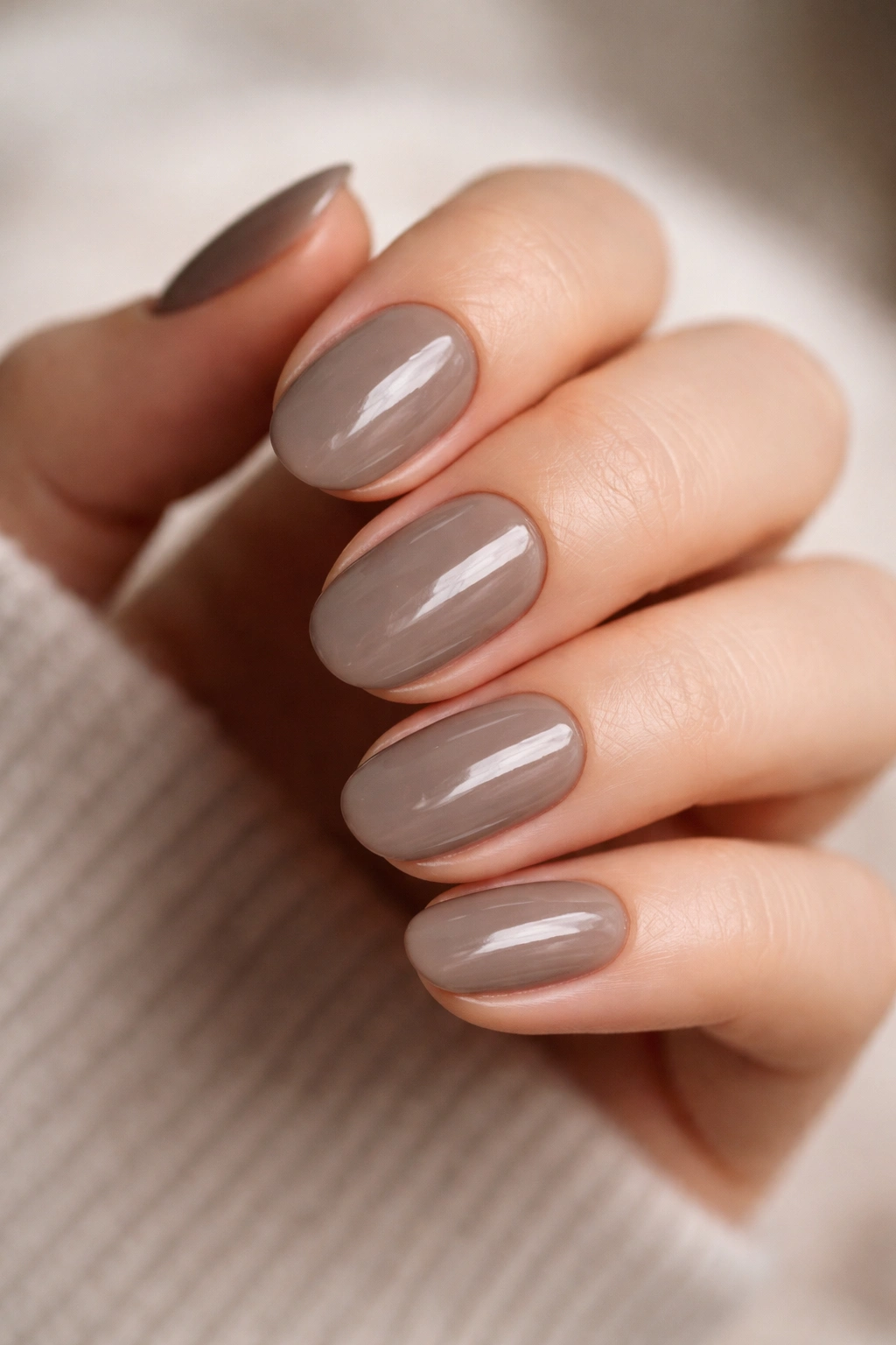 Close-up of smoky taupe short oval gel nails with glossy finish
