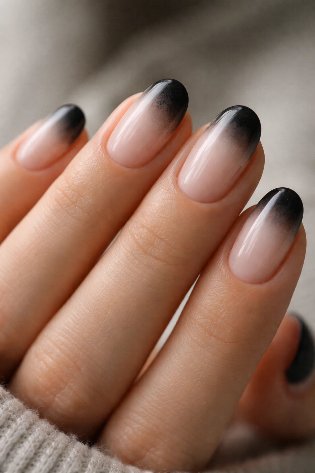 Close-up of short oval nails with smoky smudged black tips