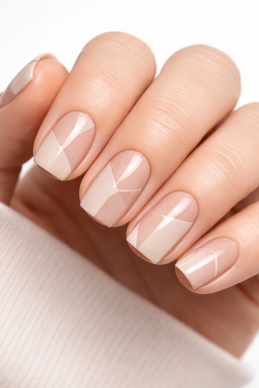 Close-up of short squoval nails with soft beige base and geometric negative-space cutouts, matte finish