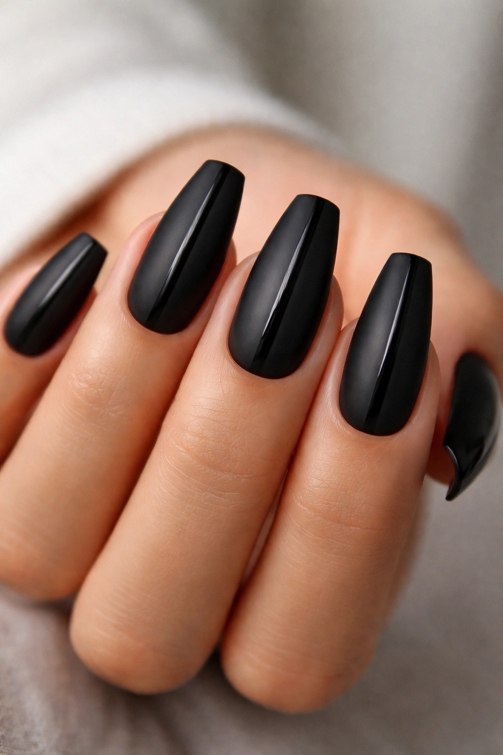 Close-up of soft black matte nails with a single gloss stripe