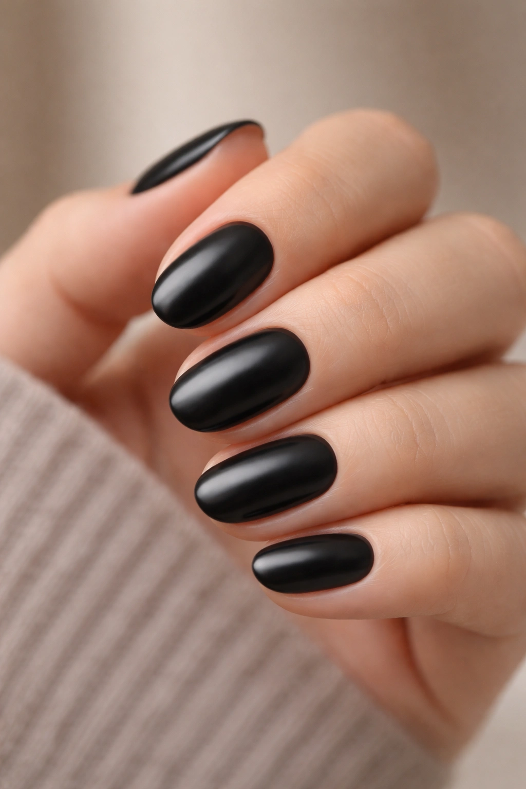 Close-up of short oval nails in soft black with a satin finish