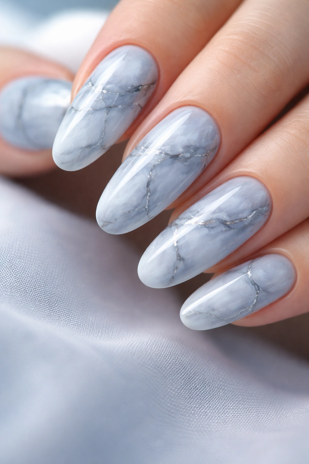 Soft blue and grey marble nails on long round nails with cool tones