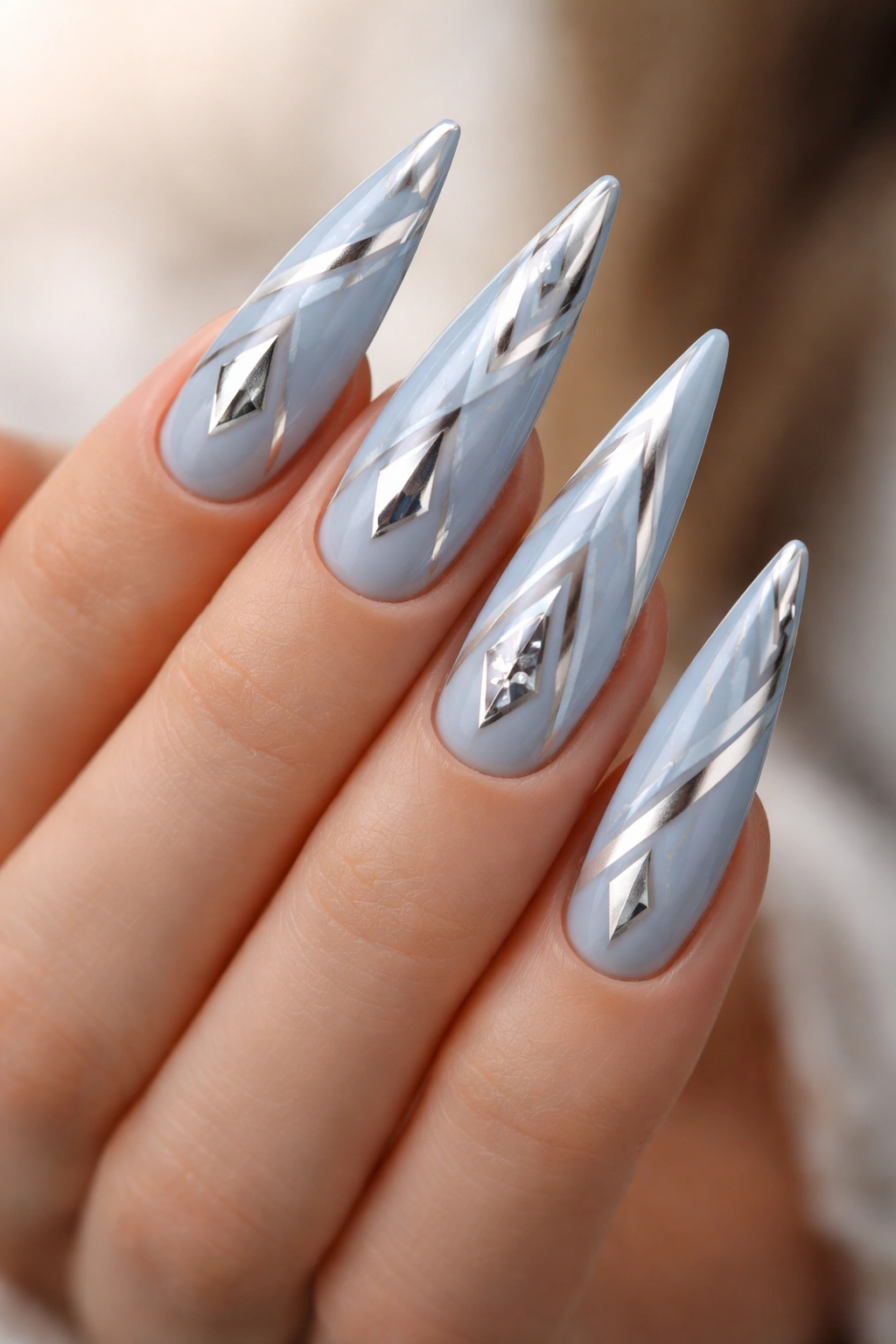 Soft blue nails with silver geometric shapes on stiletto tips