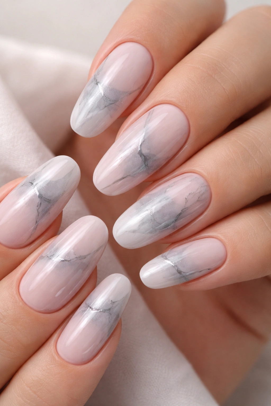 Close-up of long round nails with blush and grey marble nails