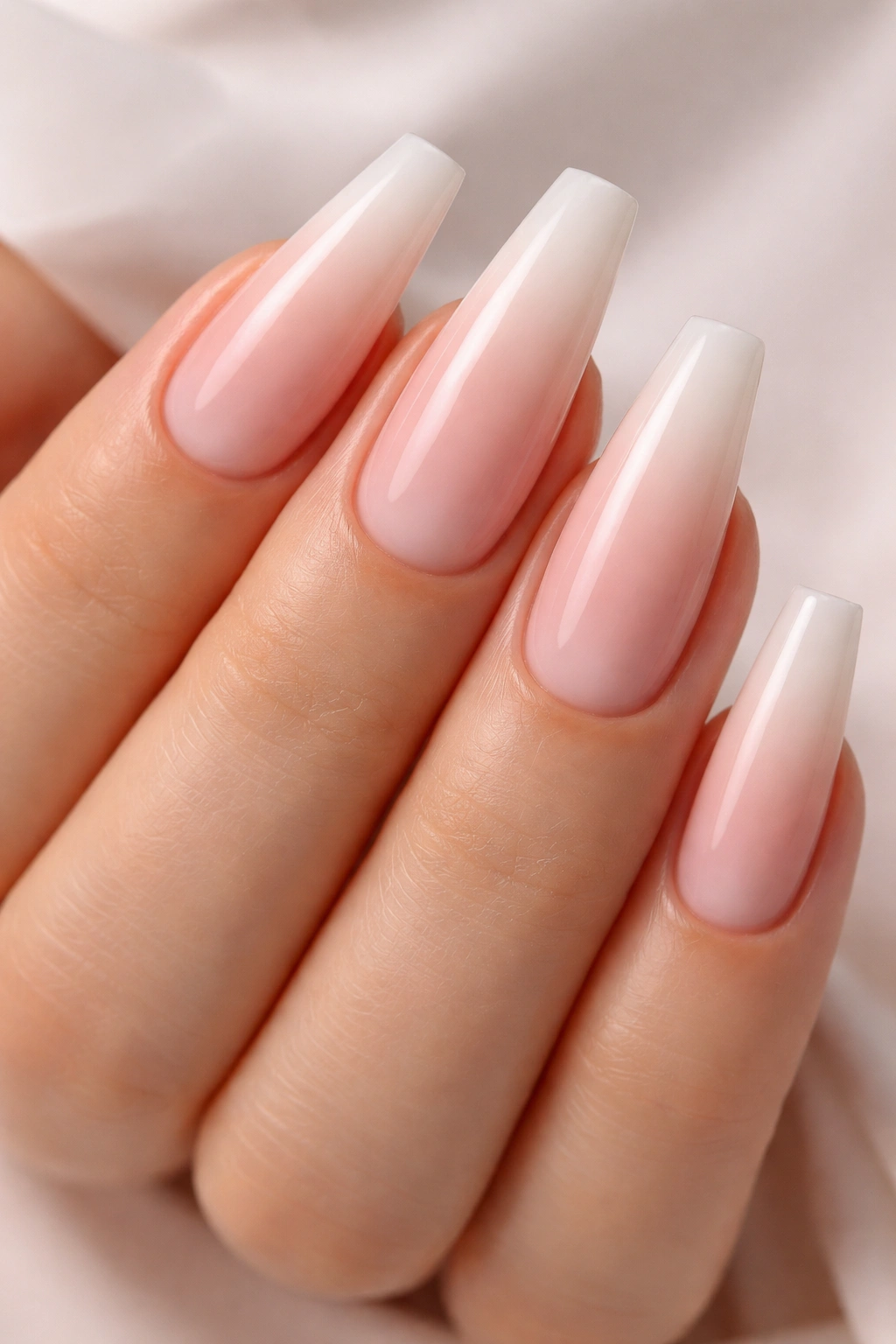 Close-up of coffin nails in soft blush milky ombre with glossy finish