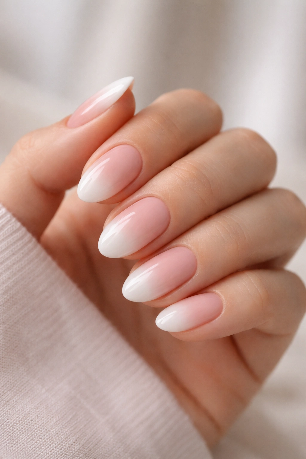 Close-up of soft French ombré almond nails with pink-to-white gradient