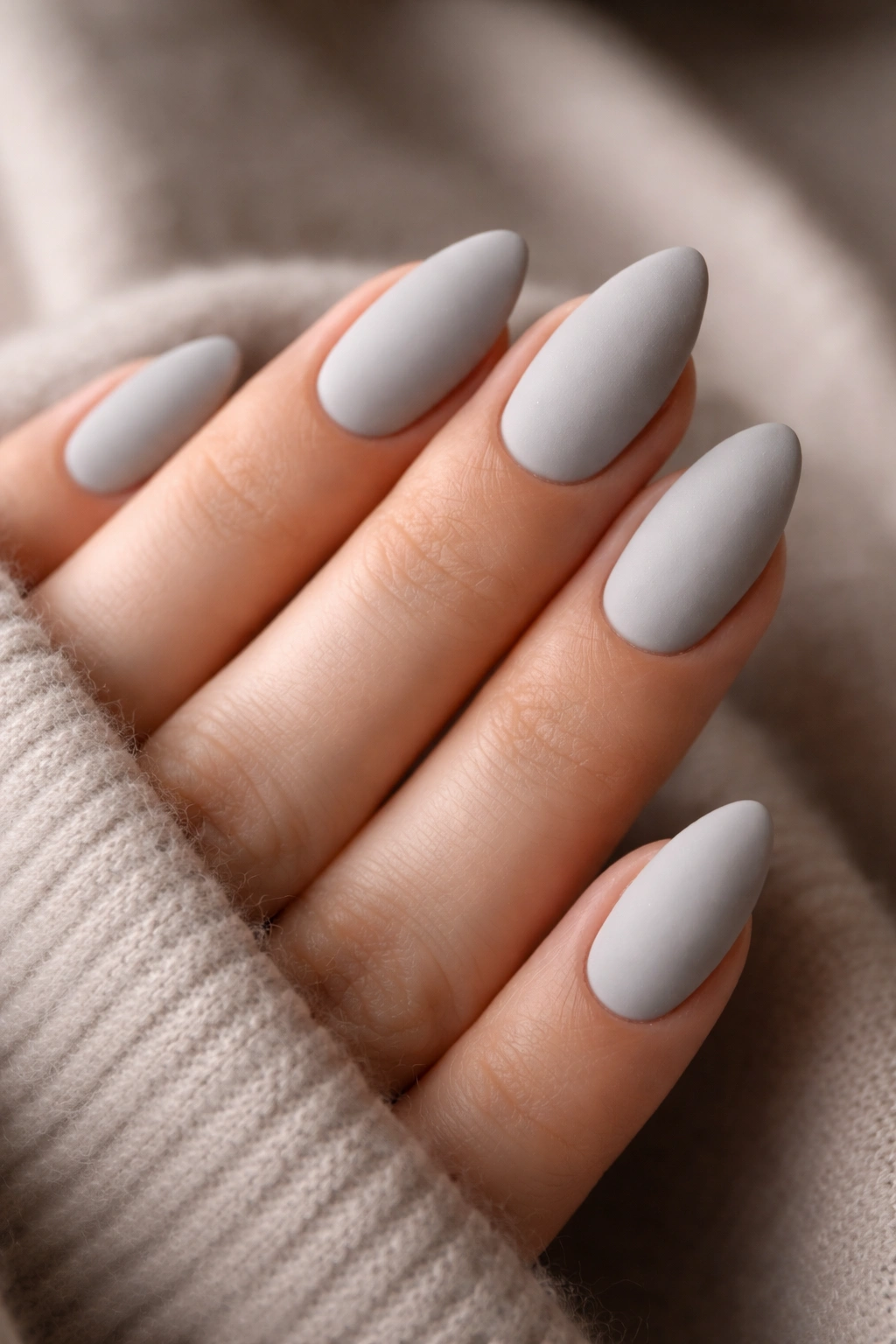 Close-up of soft gray almond nails with matte finish