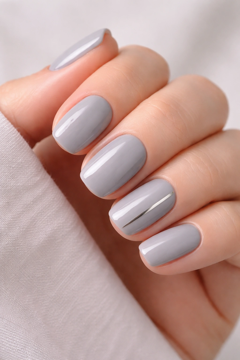 Close-up of short squoval nails in soft gray with a silver accent stripe