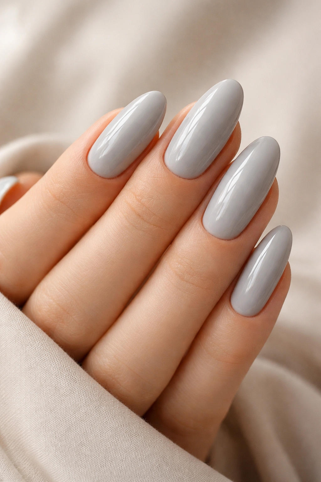 Close-up of long oval nails in soft grey with glossy finish