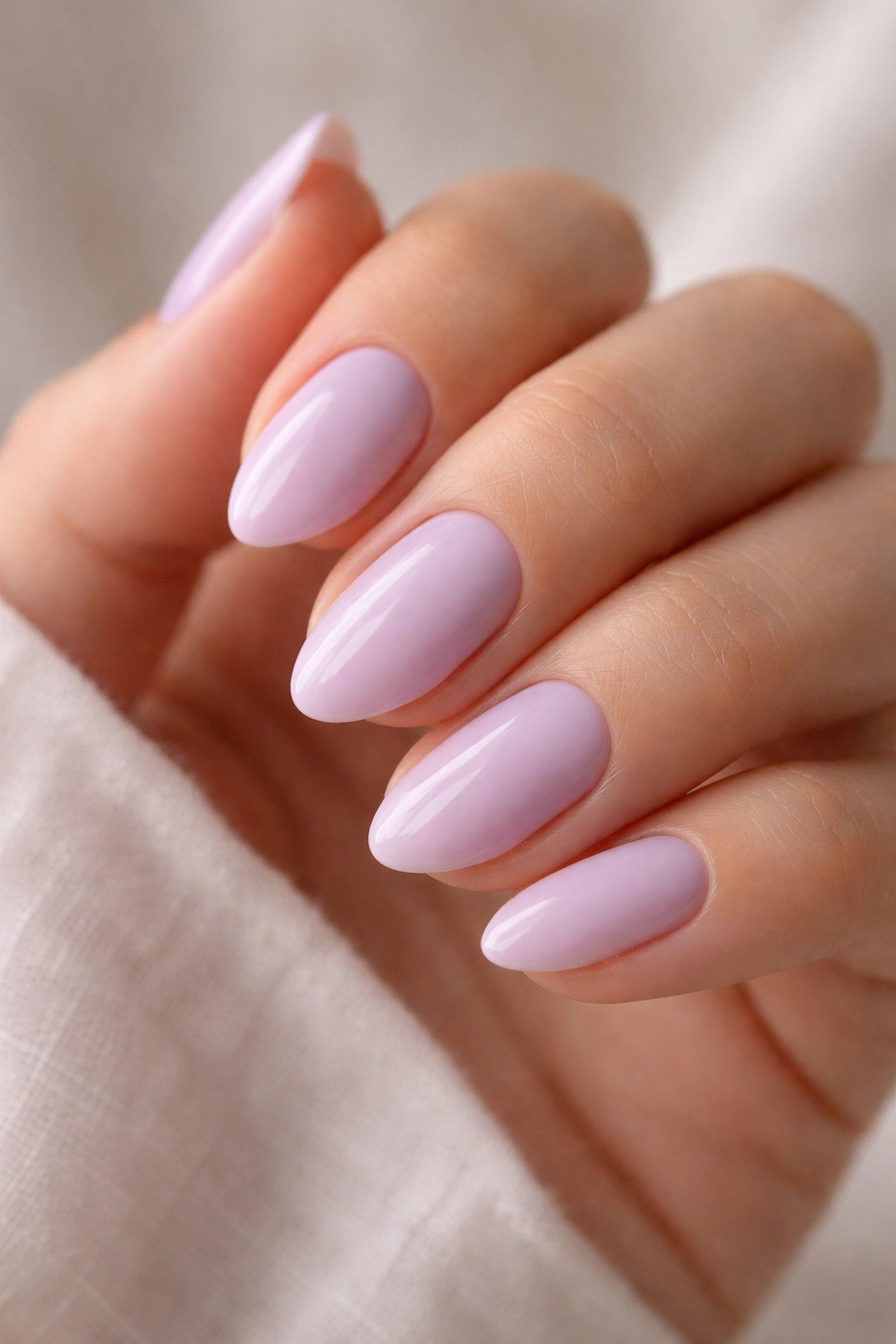 Close-up of short almond nails in pale lavender with soft rounded tips