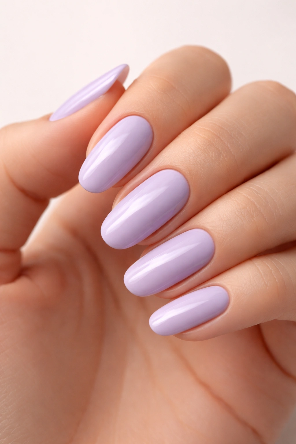 Close-up of a hand with nails painted soft lavender on a neutral background