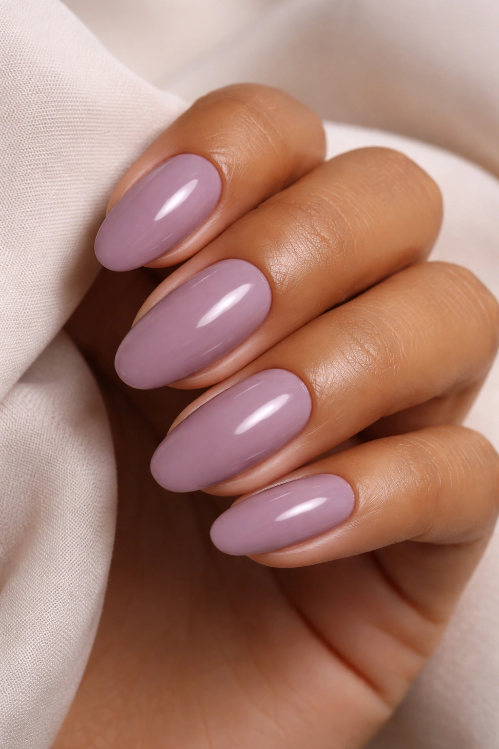 Close-up of soft mauve nails on medium skin with pink-purple tone