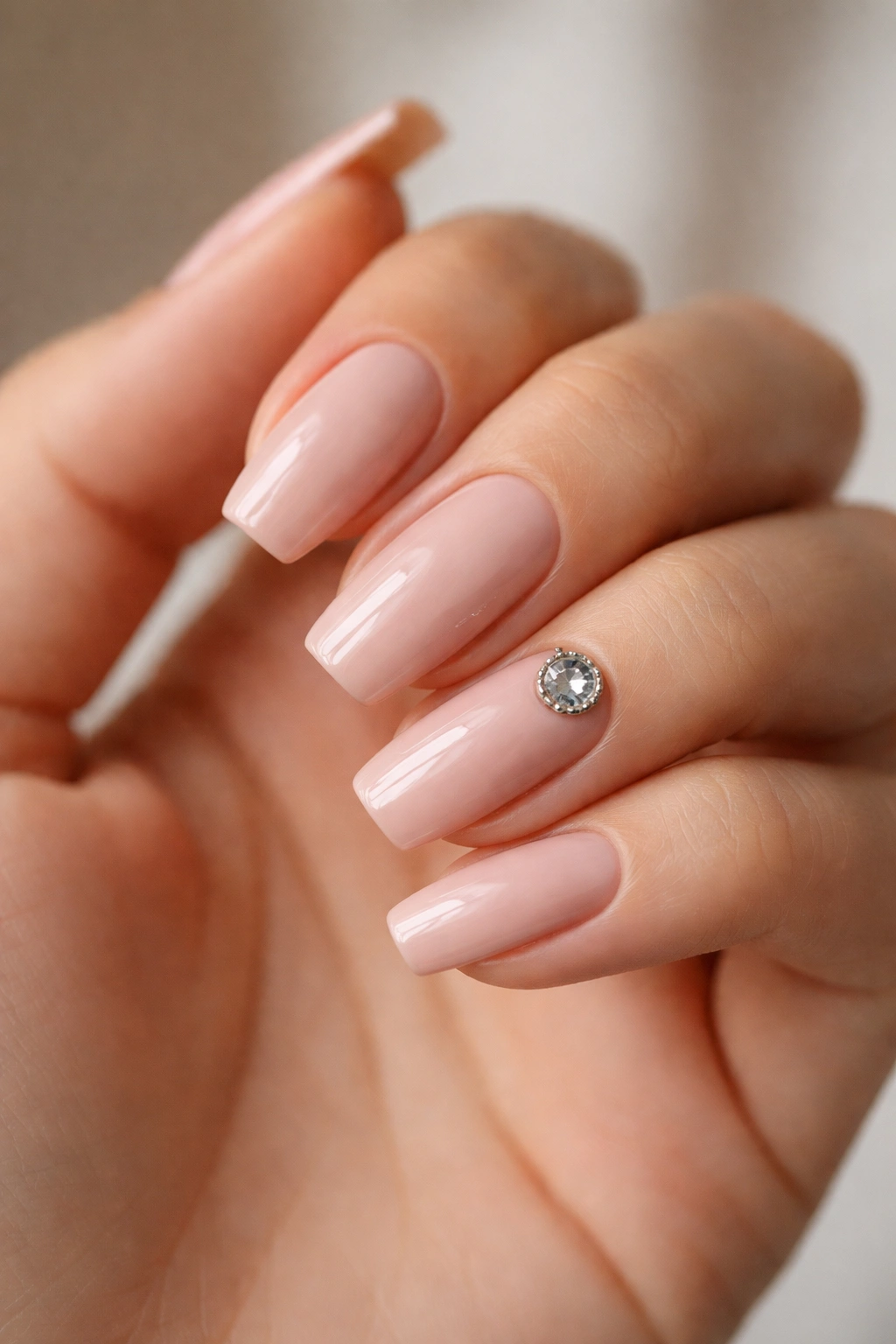 Soft nude nails with a single large accent stone on one nail