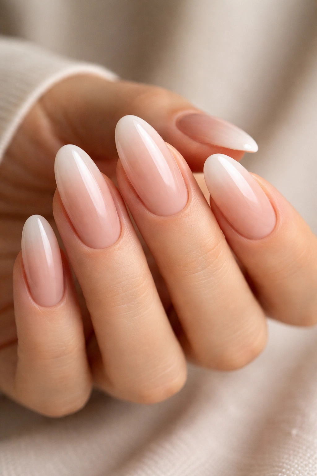 Close-up of long oval nails in a pink-to-nude ombré gradient with a glossy finish