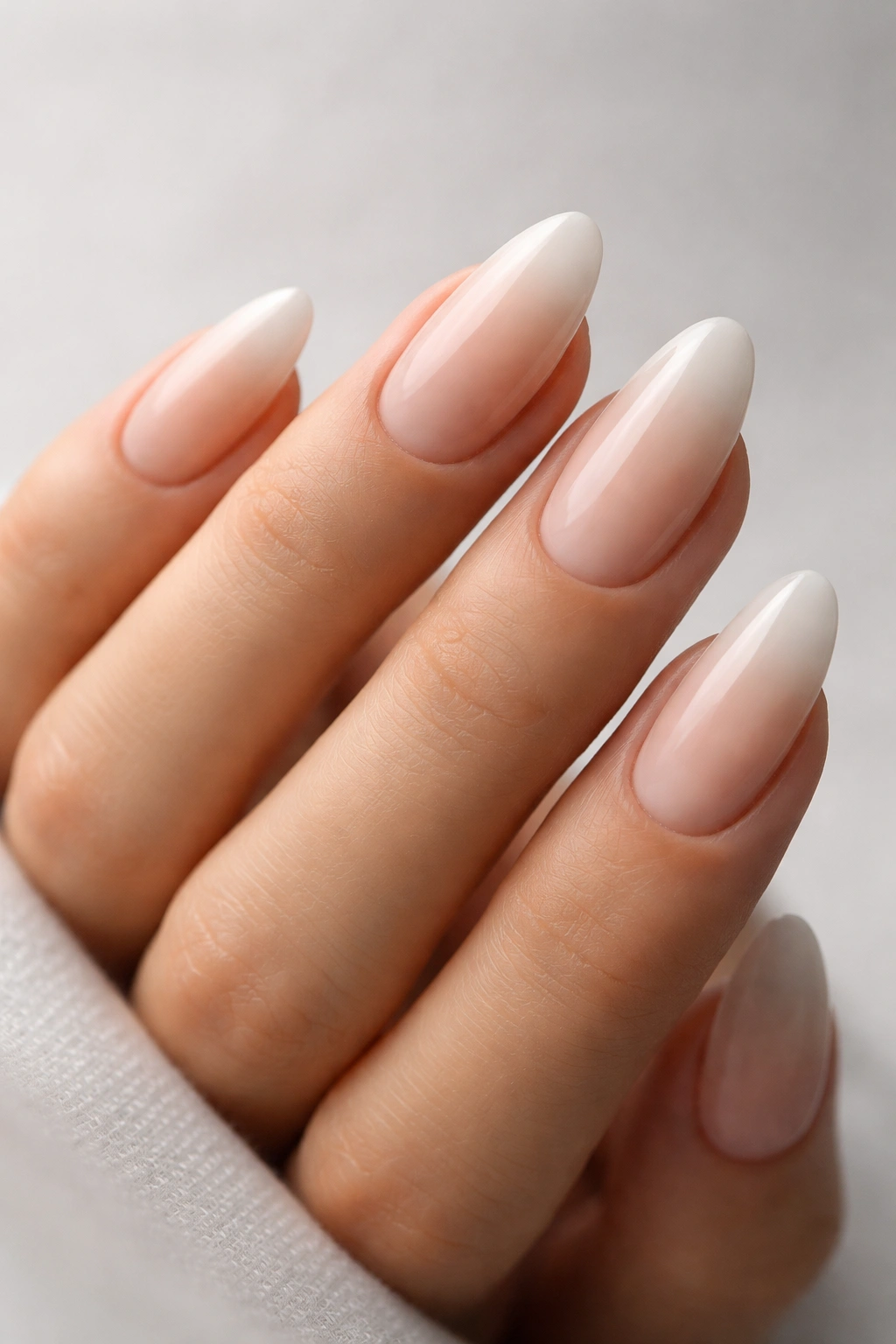 Close-up of soft ombré almond nails showing nude-to-light gradient
