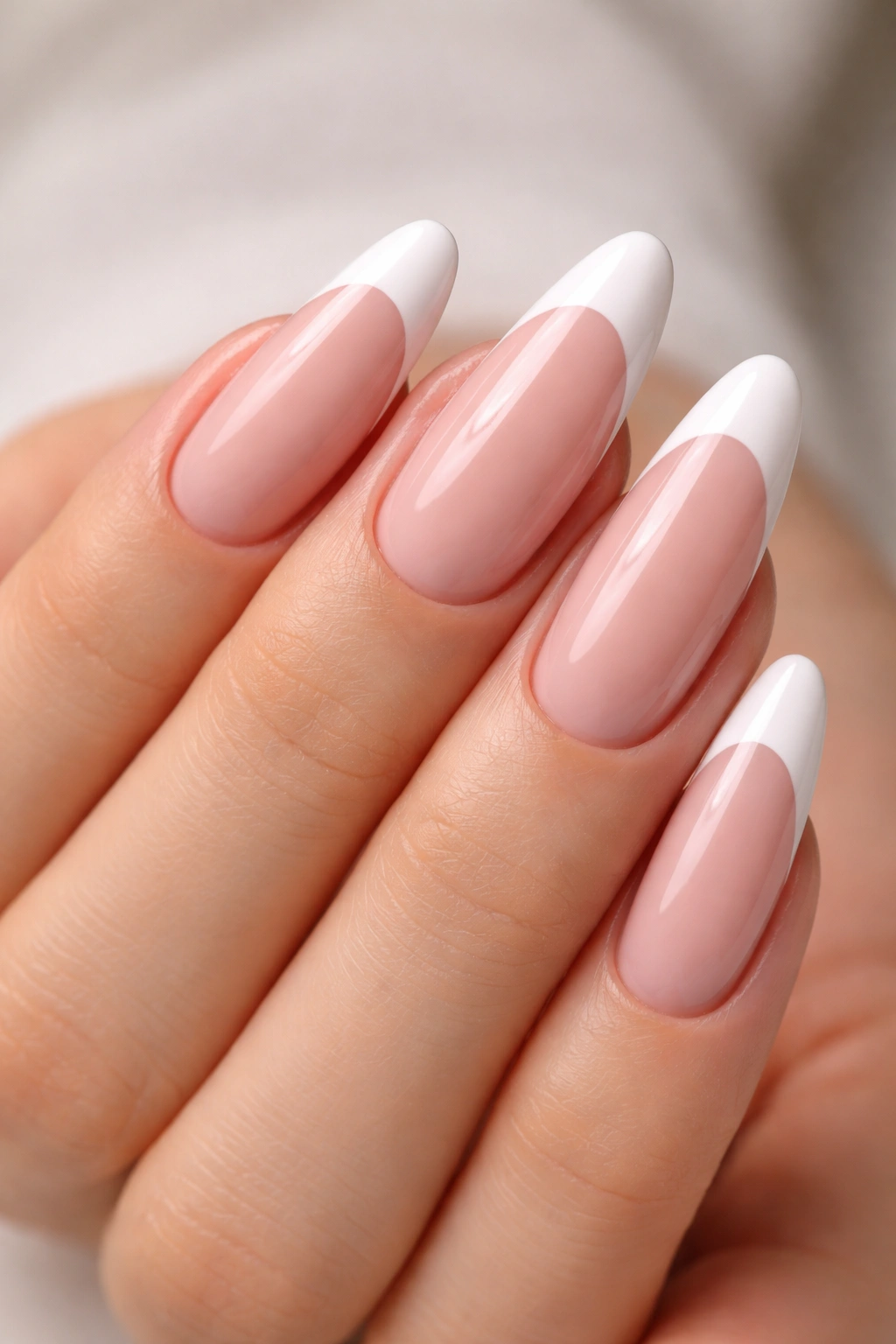 Close-up of pink builder gel nails with white crescent tips on almond nails