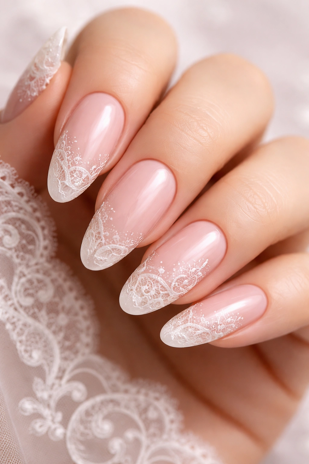 Close-up of long rounded nails with soft pink base and white lace along tips and sides