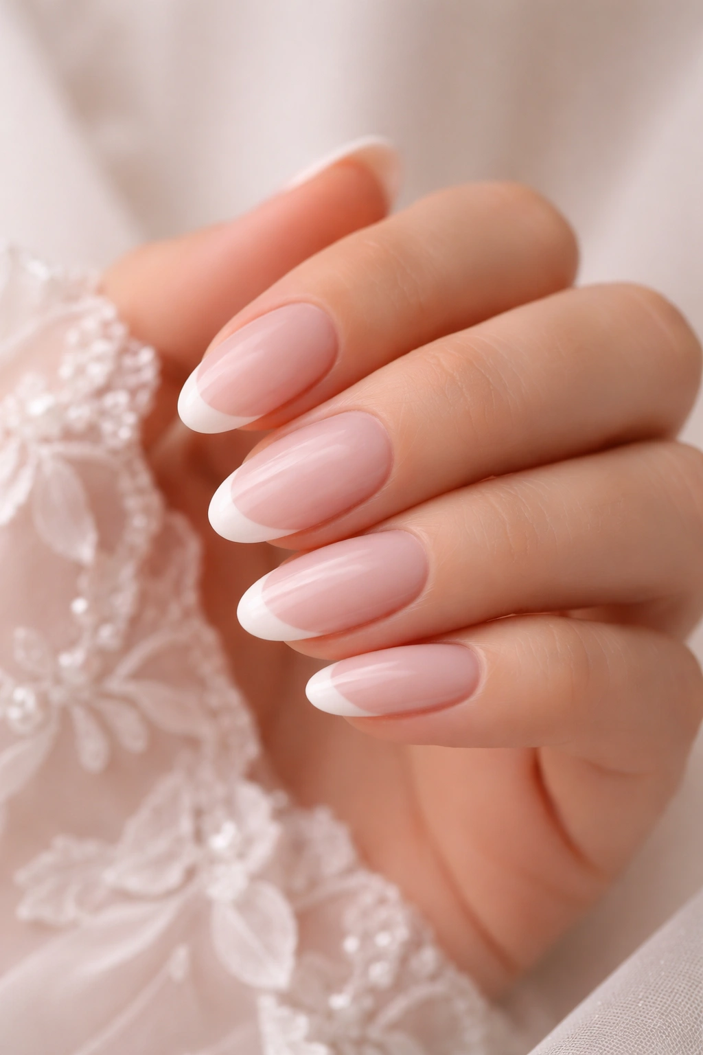 Close-up of an almond-shaped nail with sheer pink base and white tip