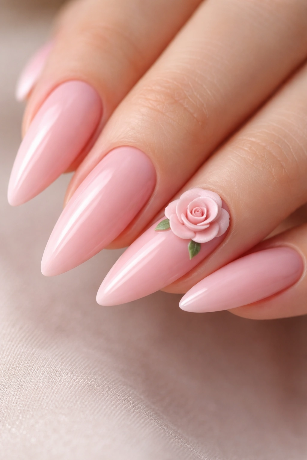 Soft pink stiletto nails with a small 3D rose on the ring finger