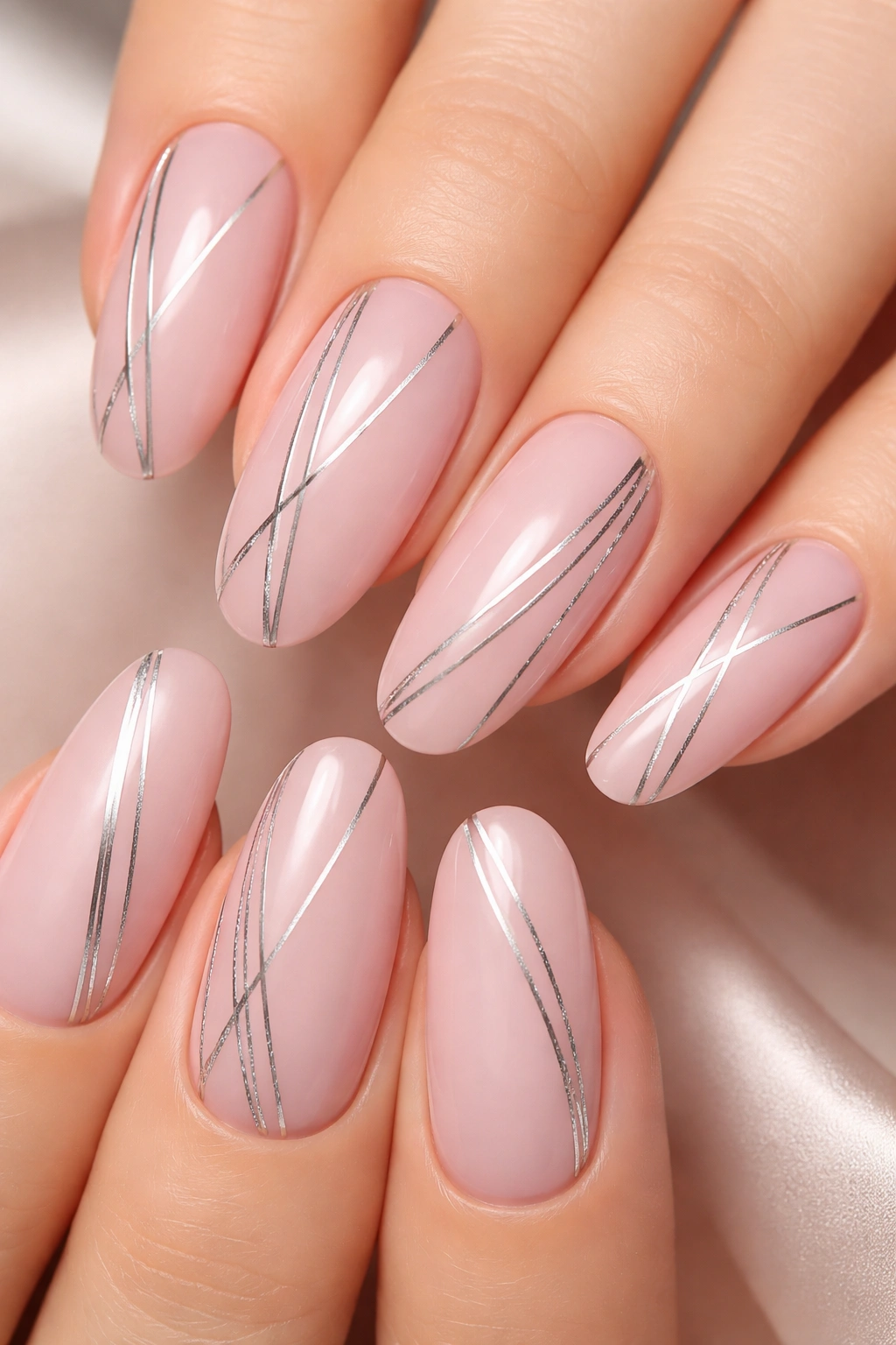 Close-up of soft pink nails with silver pinstripe details on long oval nails