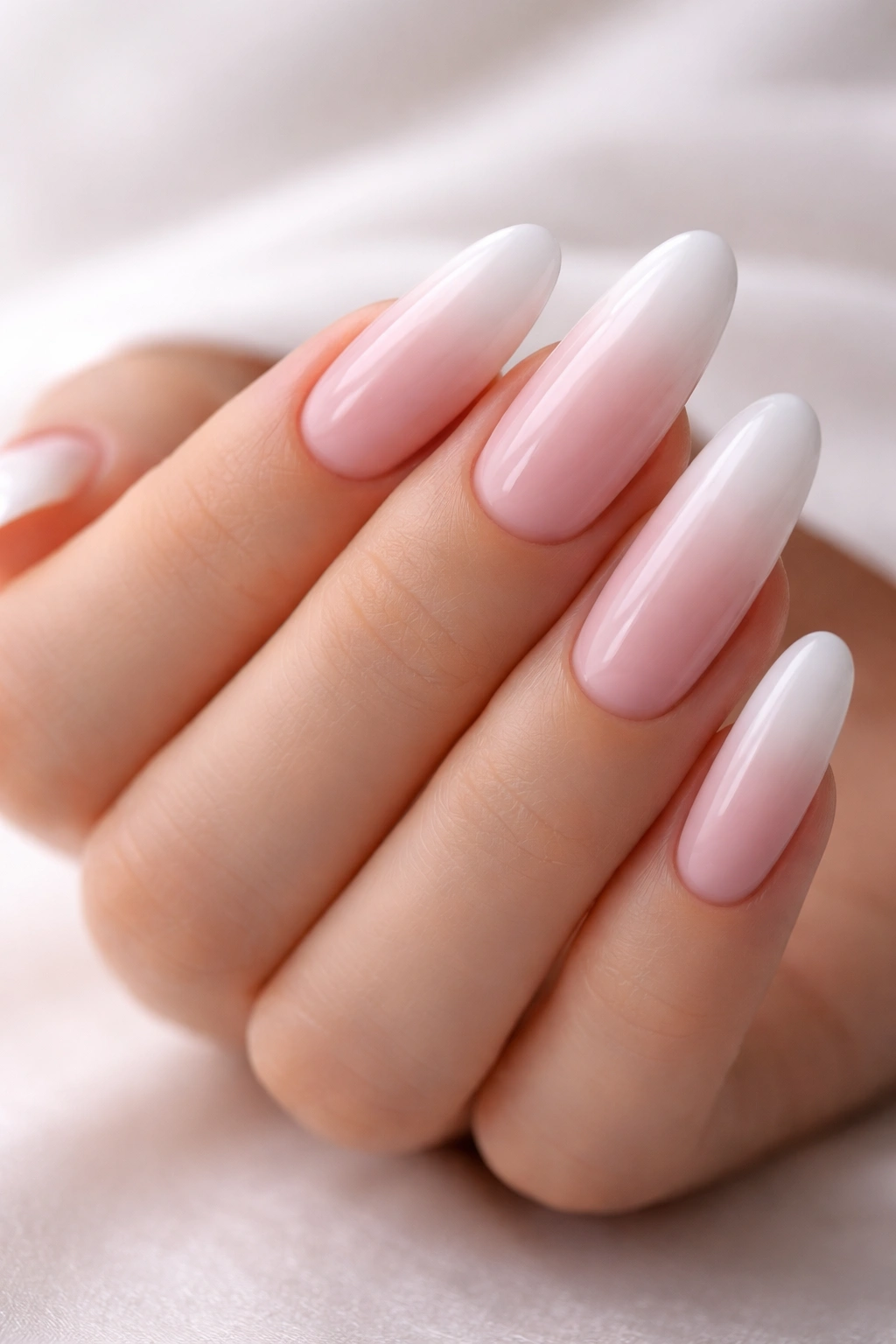 Close-up of soft pink to white gradient on long oval nails