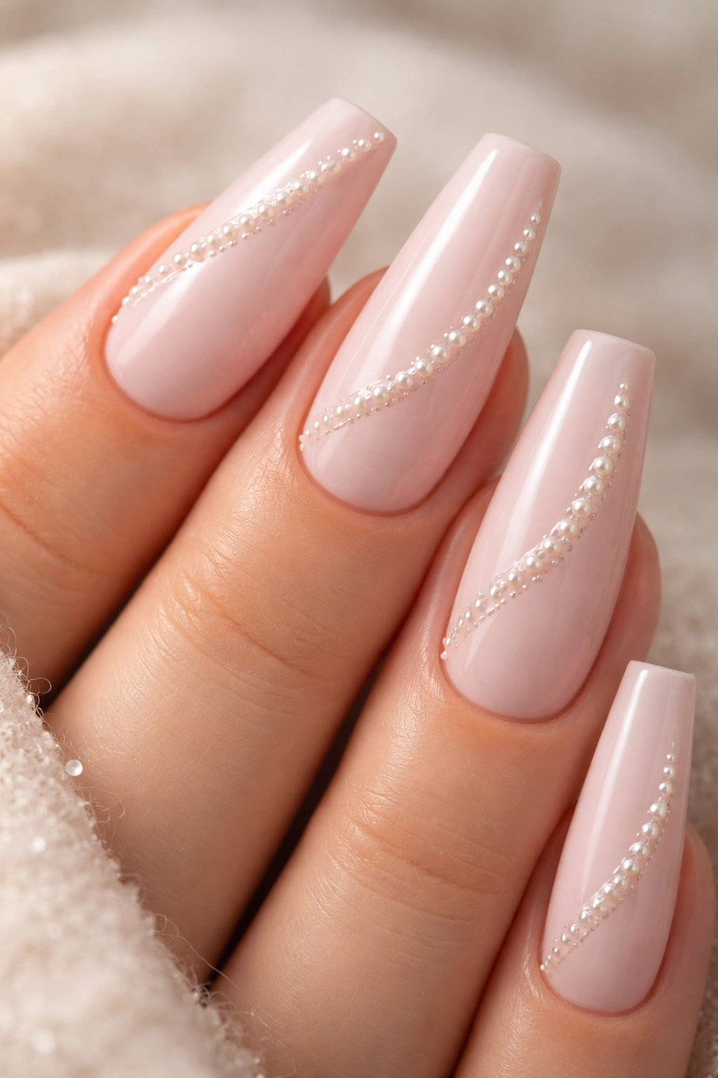 Close-up of soft pink coffin nails with pearl inlays for subtle texture