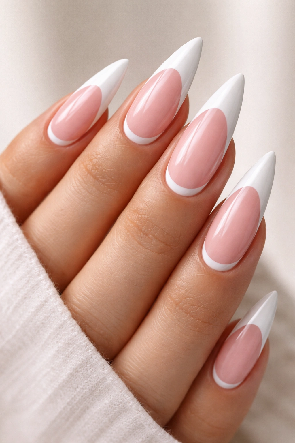 Soft pink stiletto nails with white reverse French manicure at cuticle.