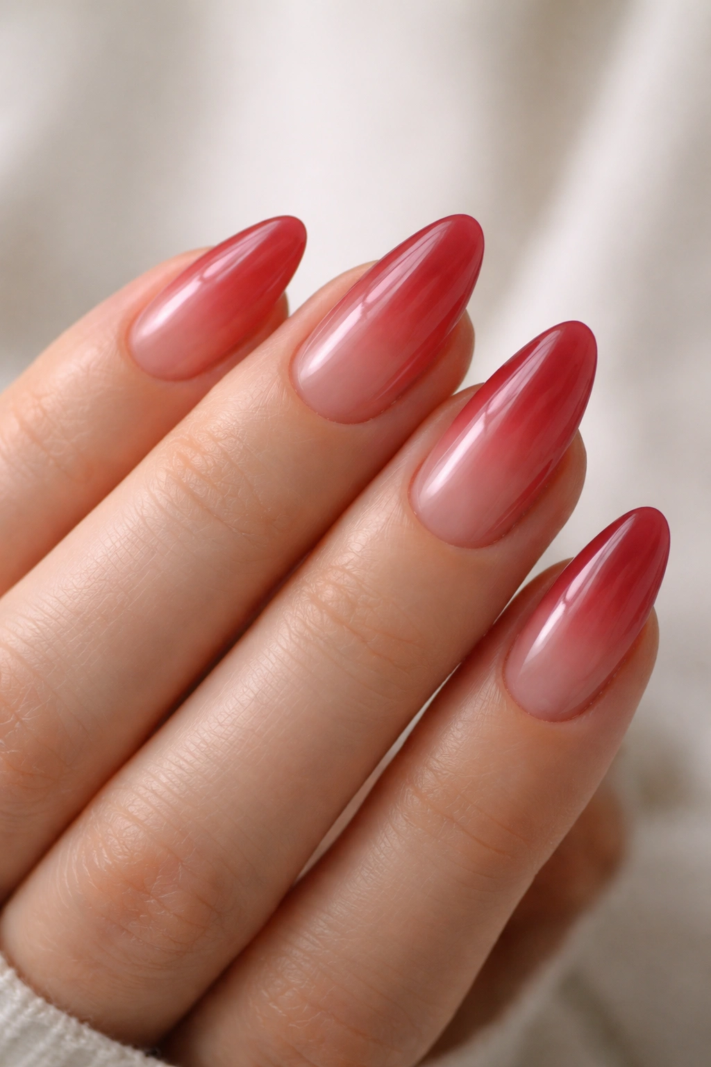 Close-up of sheer red almond nails with translucent finish