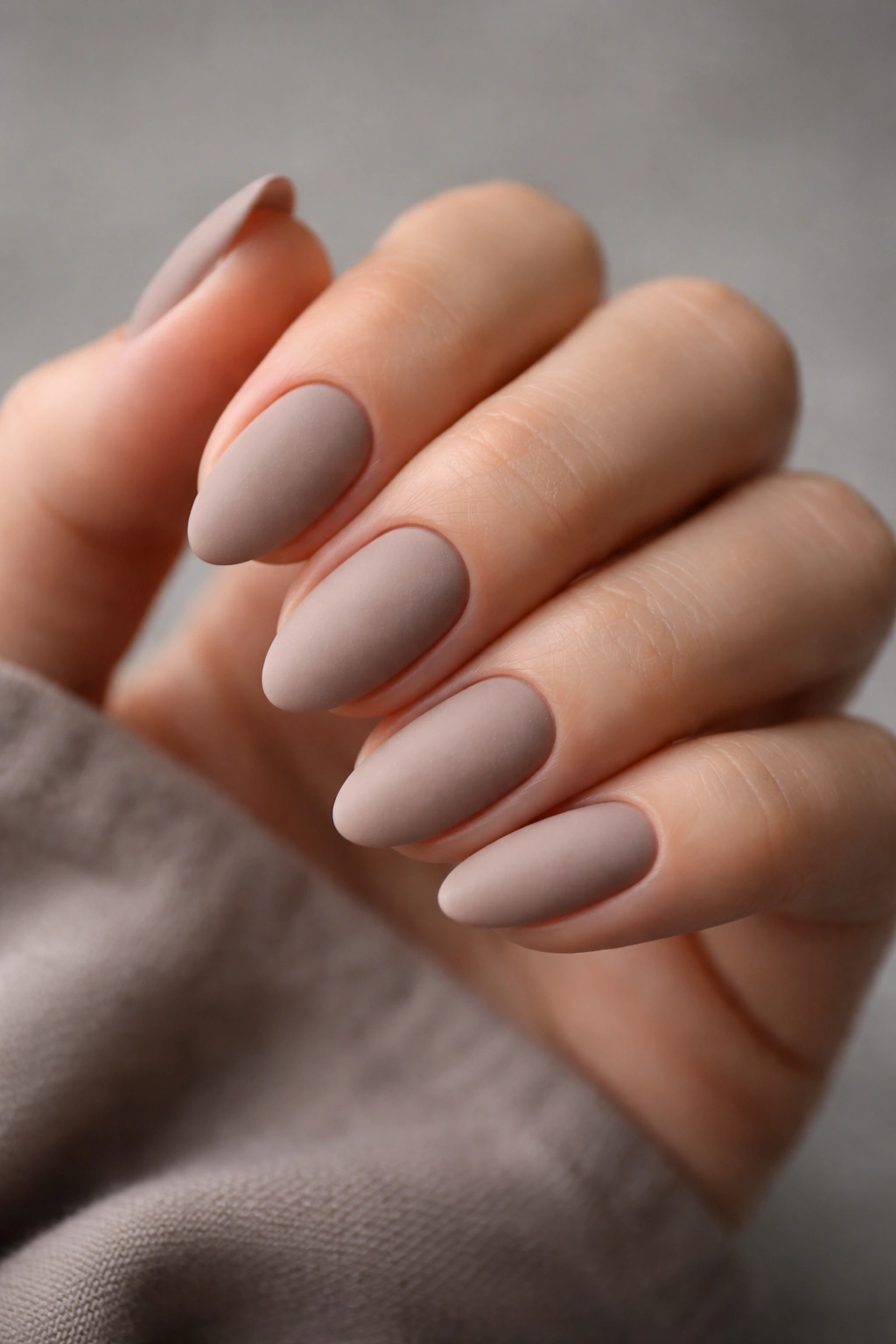 Close-up of short almond nails in matte taupe velvet finish