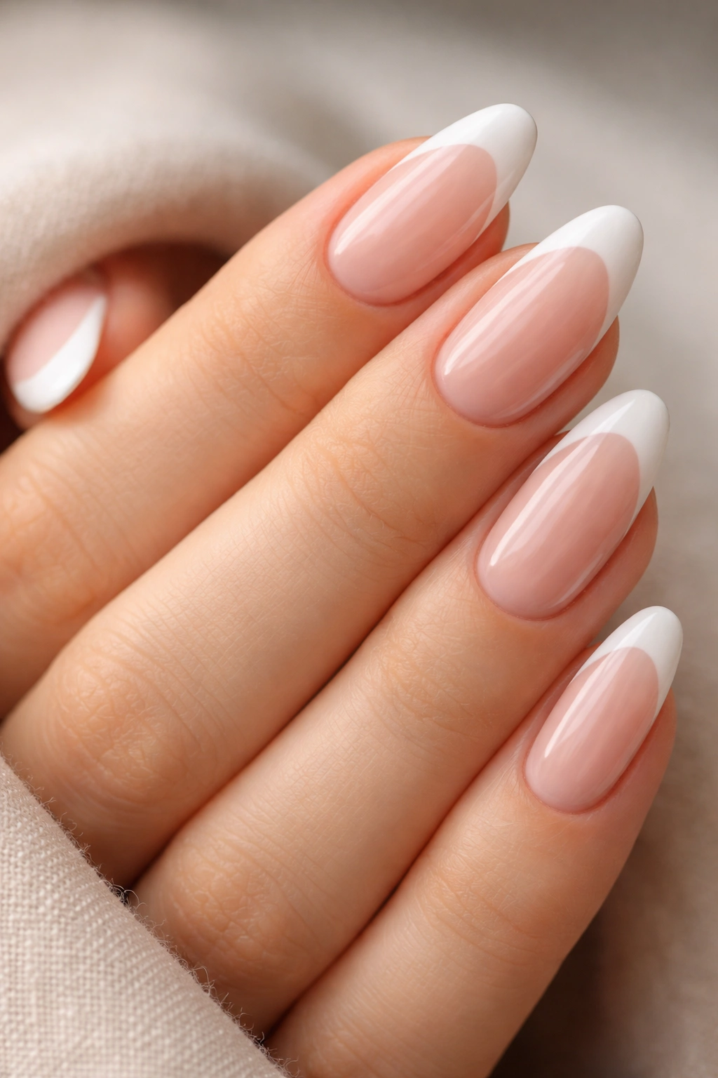 Close-up of almond nails with soft white French tips.