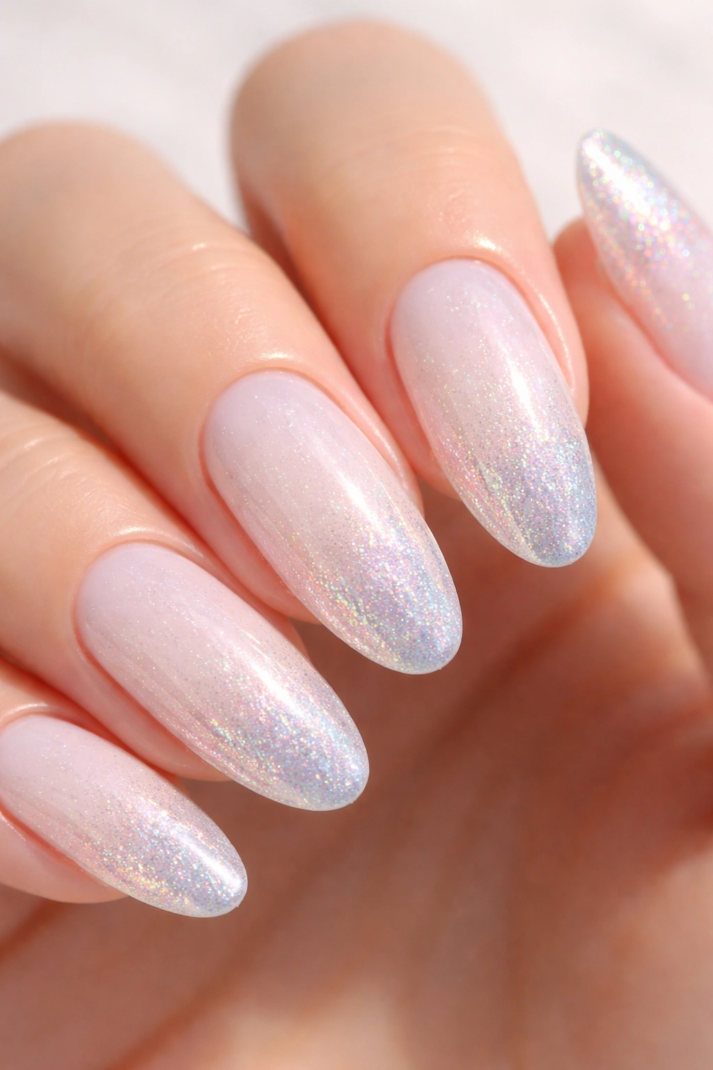 Close-up of soft white nails with iridescent glitter gradient