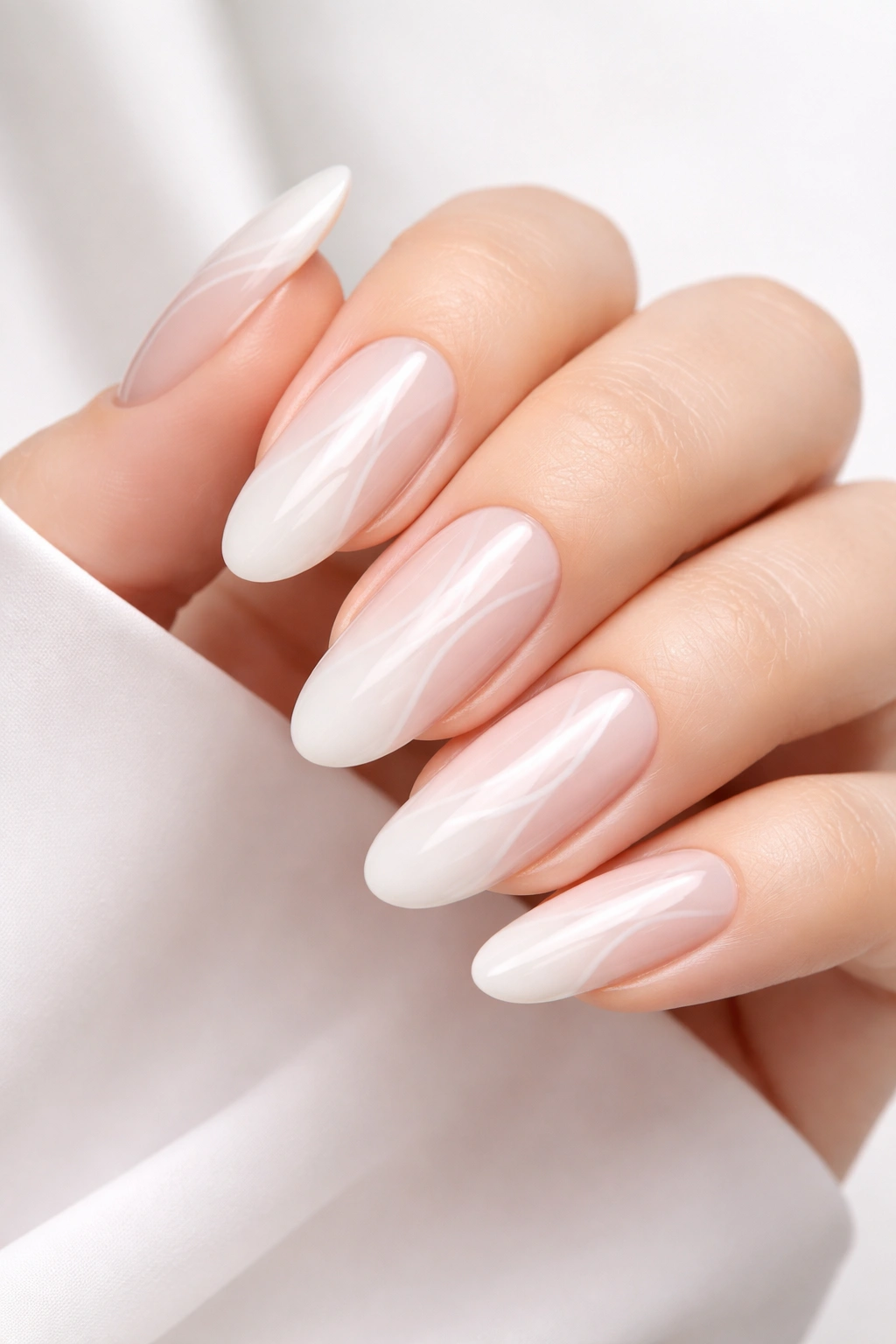Close-up of long round nails in soft white with curved negative space design