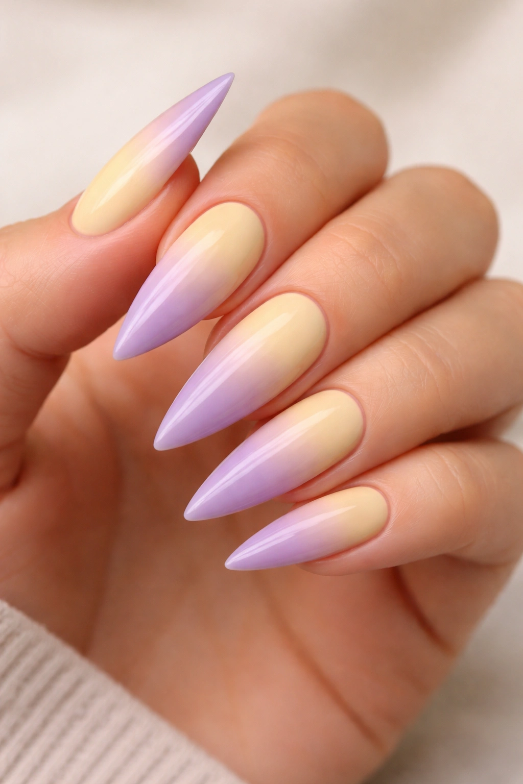 Close-up of soft yellow to purple ombre stiletto nails