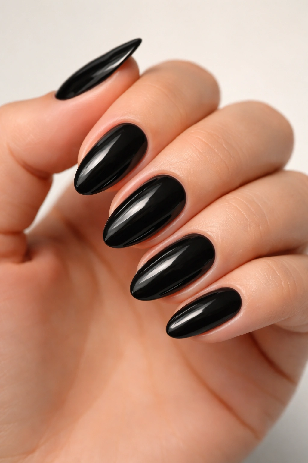 Close-up of solid black almond nails with precise cuticle lines